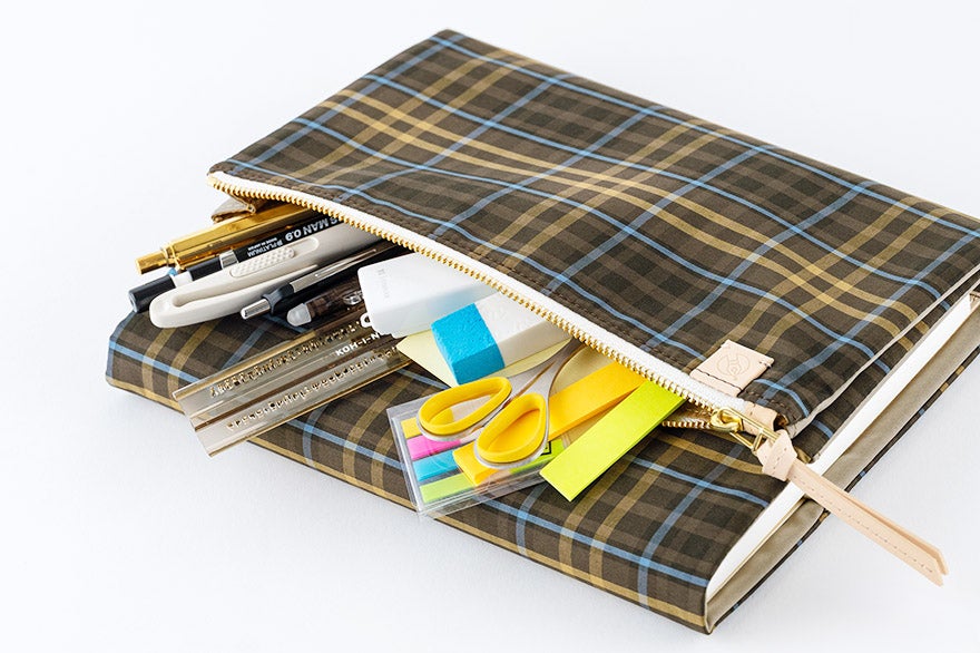 A plaid polyester A5 book cover (cousin size) with a zipper, shown holding pens and stationery.