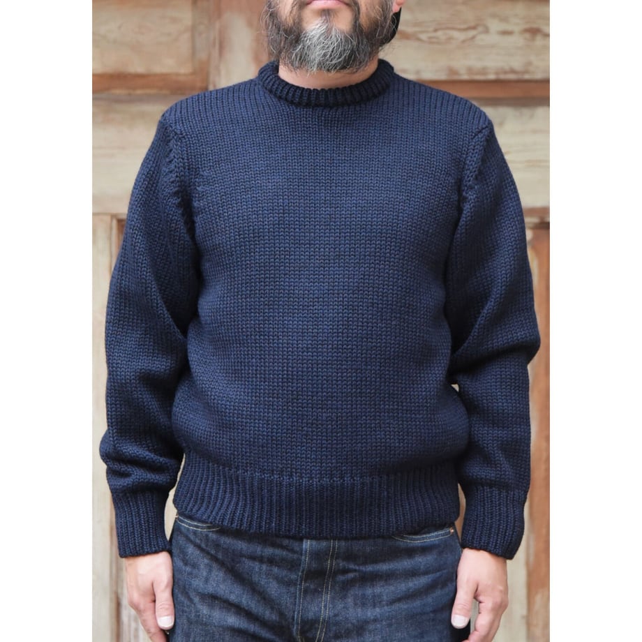 Front view of a navy wool sweater (TRAILBLAZER) worn by a model against a wooden background.