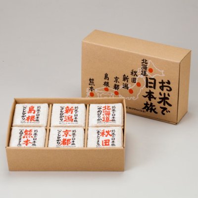 A cardboard gift box with Japanese text beside six individually wrapped rice packets arranged in two rows.