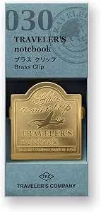 Packaged Traveler's Company brass clip for Traveler's Notebook with an airplane pattern visible on the clip.