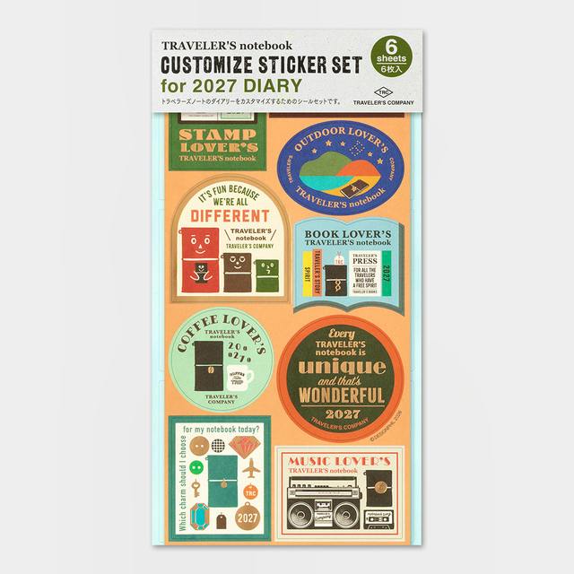 Sheet of Traveler's Notebook customization stickers for the 2027 diary showing multiple circular and rectangular label designs.