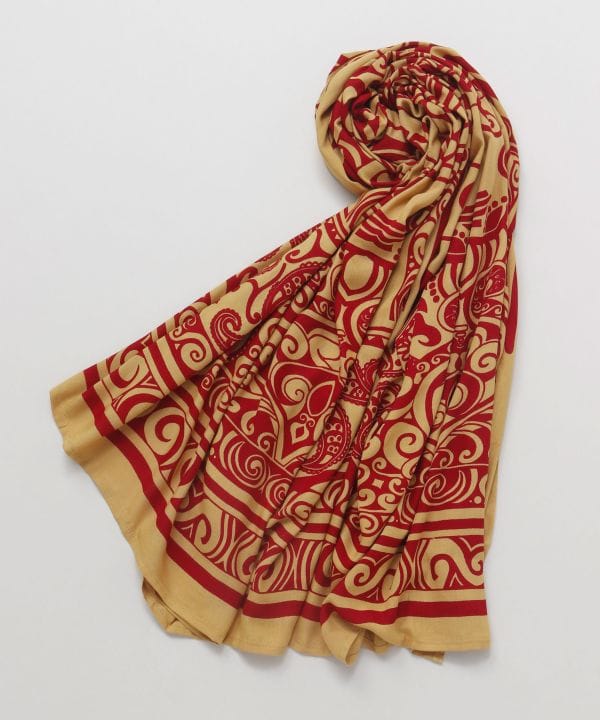 Red and beige tribal-pattern rayon scarf (pareo) laid flat and partially rolled on a white background.