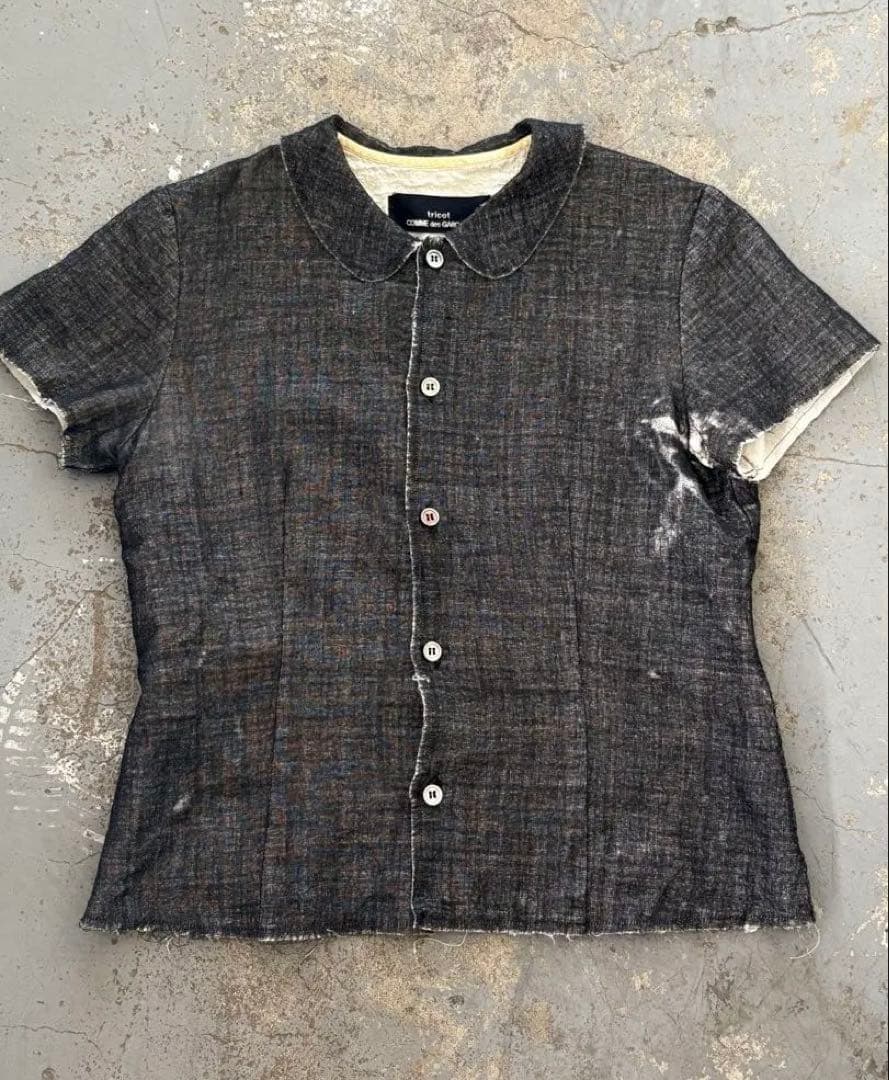 Front view of the tricot COMME des GARCONS women's short-sleeve cotton blouse laid flat, showing a button-front and rounded collar.