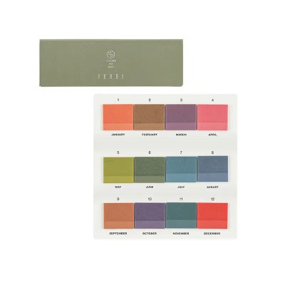 Studio photo of the TSUKI no IRO translucent sticky note tiles showing a twelve-color sample board and the green product box.