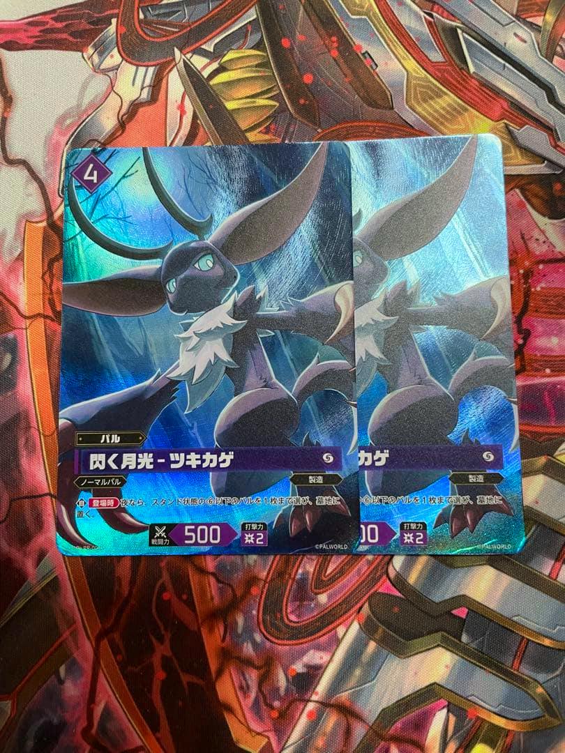 Two holographic promo trading cards titled “閃く月光-ツキカゲ” shown overlapping on a playmat.