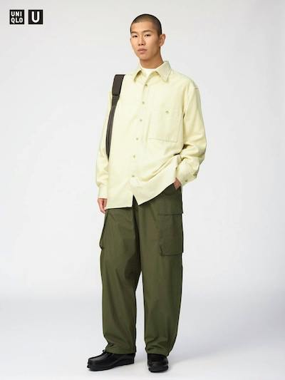 A model stands wearing the men's relaxed wide cotton pants with large side cargo pockets and a light-colored shirt against a plain background.