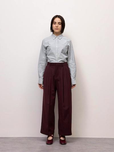 Front-facing model wearing the burgundy wide tuck pants with a tucked light-gray button-up shirt.