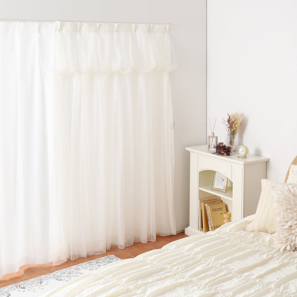Ivory tulle balloon double curtain hanging over a window in a bedroom setting.