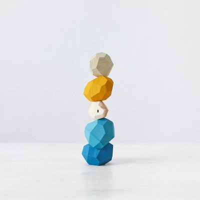 Wooden tumi-isi stacking figure composed of five faceted pieces in cream, yellow, and blue tones on a white background.