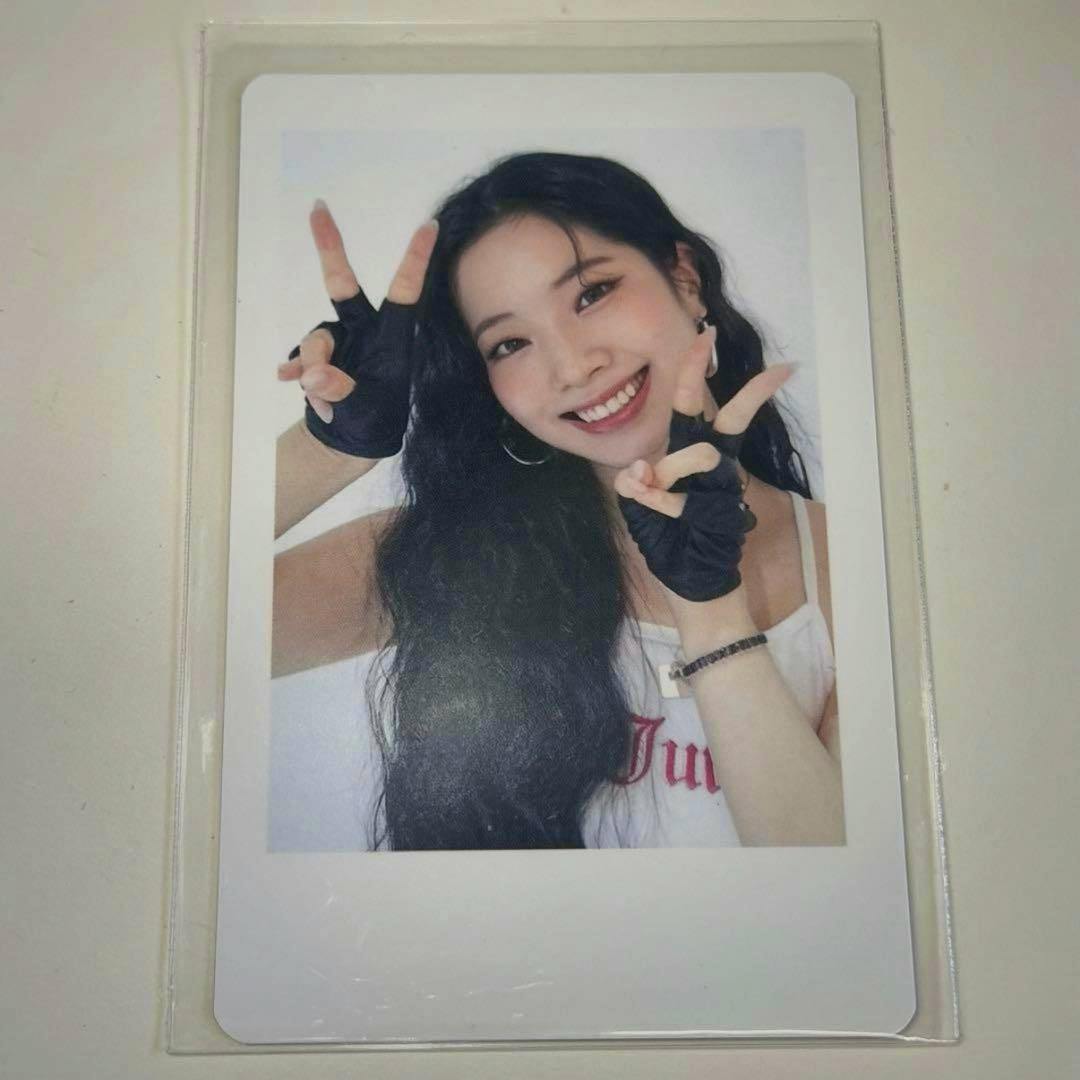 Photocard inside a clear plastic sleeve showing a smiling woman wearing black fingerless gloves and making peace signs.