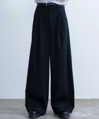 Front view of a model wearing the two-tuck wide straight striped slacks, full-length dark striped pants.