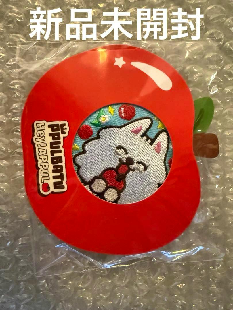 Front view of the packaged embroidered can badge on an apple-shaped red backing showing a white embroidered cartoon cat holding a red object.