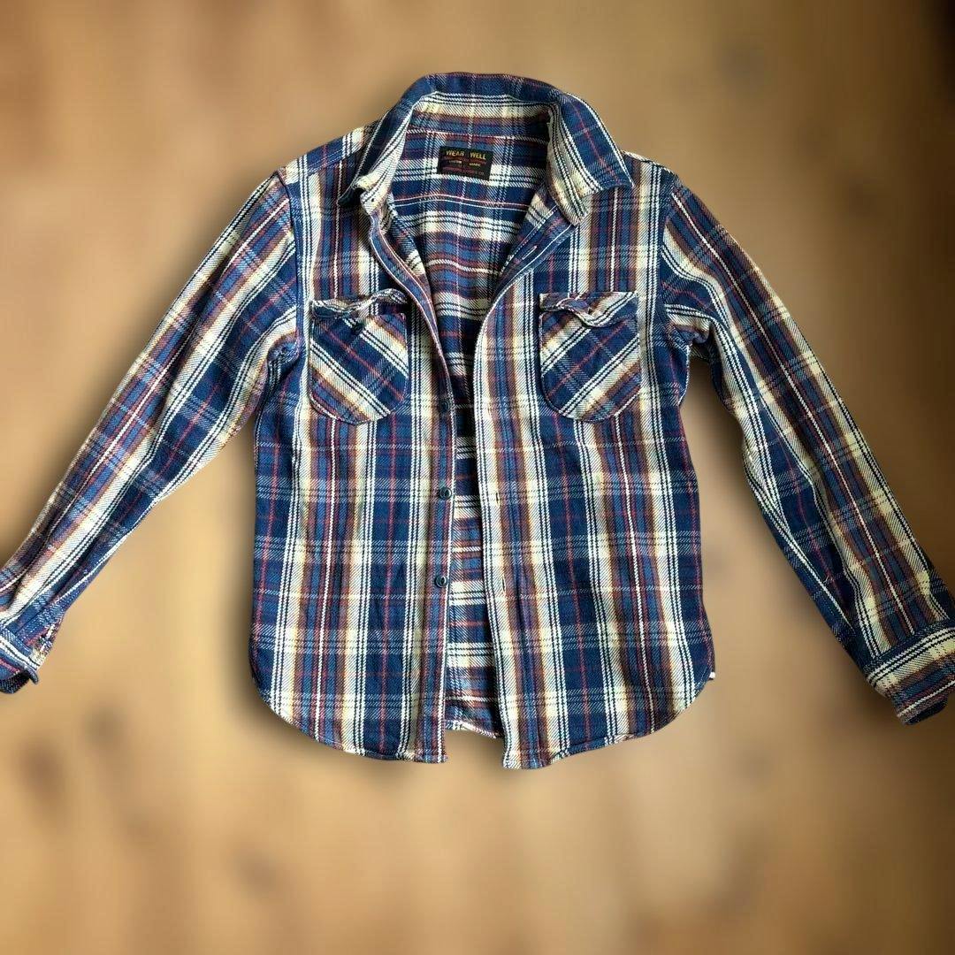 Blue plaid men's cotton flannel shirt laid flat with sleeves extended.
