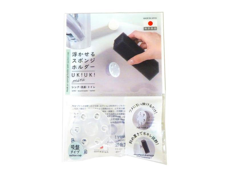Clear retail packaging showing the transparent suction-cup sponge holder and a photo of it holding a sponge near a sink.