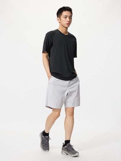 Male model wearing light-gray men's polyester shorts and a black t-shirt, standing against a white background.