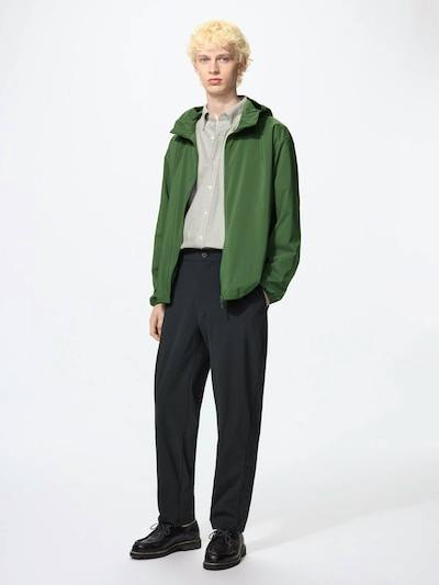 Male model wearing the men's nylon pants in dark color, paired with a green jacket and light shirt, standing against a white background.