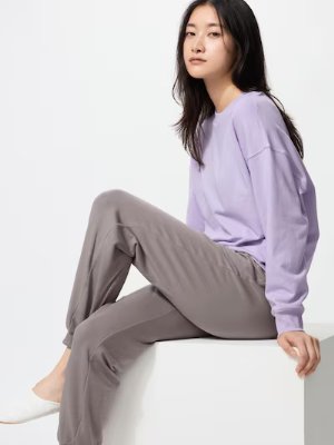 Model seated wearing a lavender long-sleeve top and gray pants from the set.