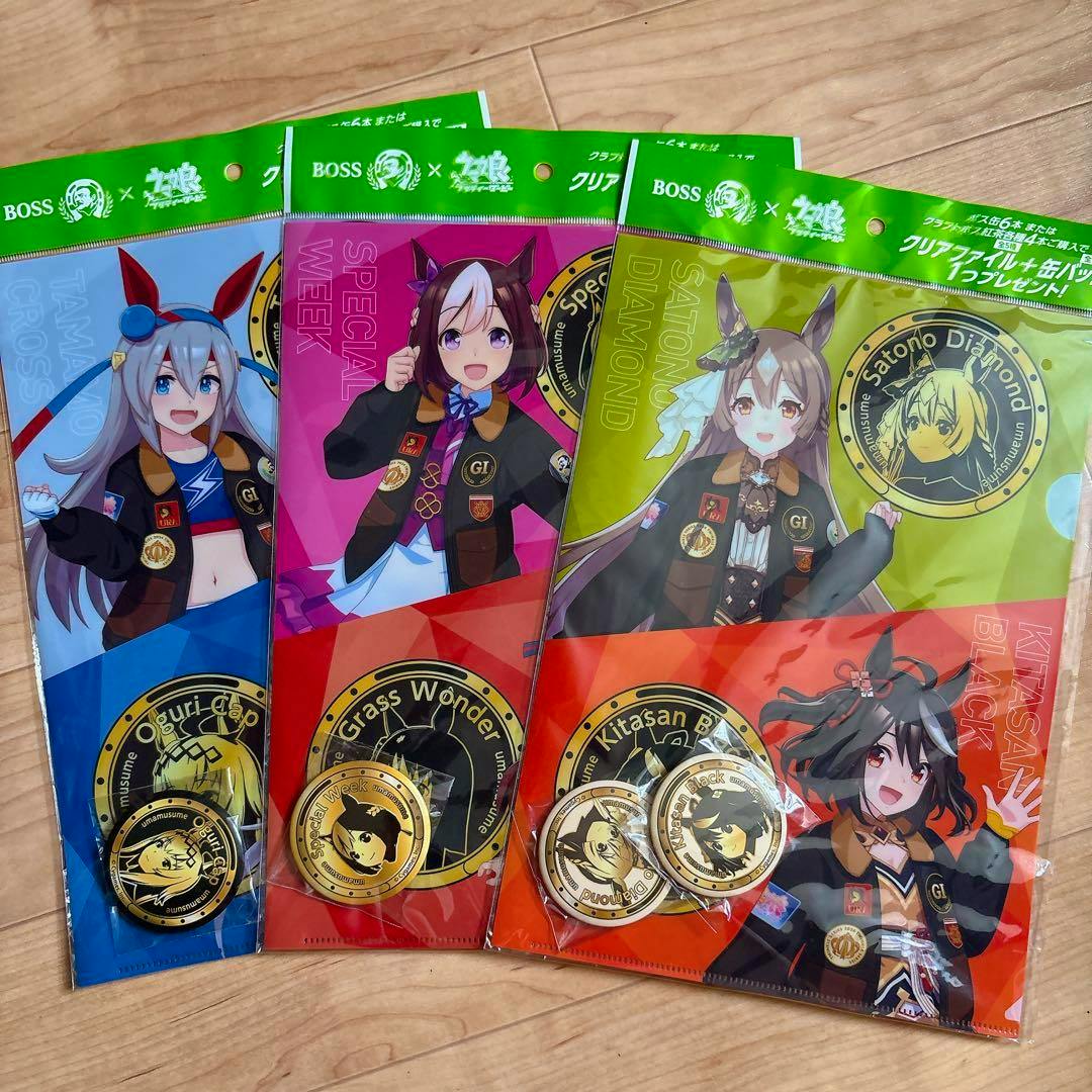 Three packaged Uma Musume × BOSS collaboration clear files with their round can badges displayed on a wooden surface.