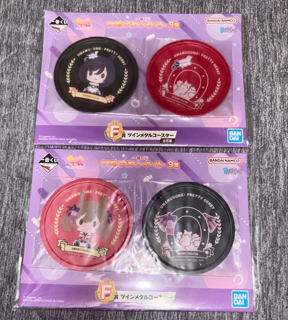 Packaged Umamusume (ウマ娘) twin metal coaster set showing four character-illustrated coasters in two blister cards on a gray surface.