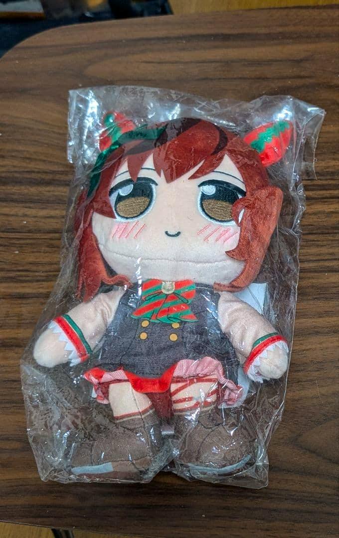 Front view of the Uma Musume Pretty Derby "Nice Nature" plush toy inside clear plastic packaging on a wooden surface.