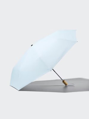 White umbrella with a wooden handle open and resting on a flat surface.