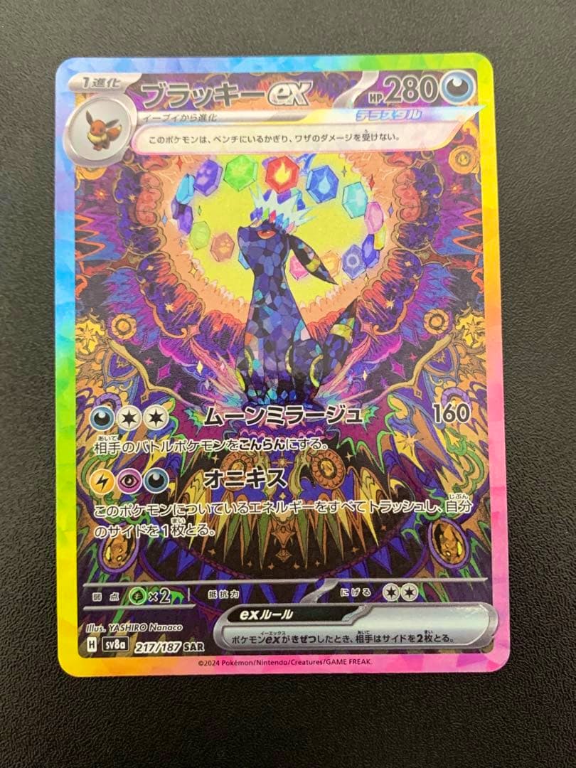 Front of a holographic Japanese Pokémon trading card titled ブラッキーex shown face-up on a black background.