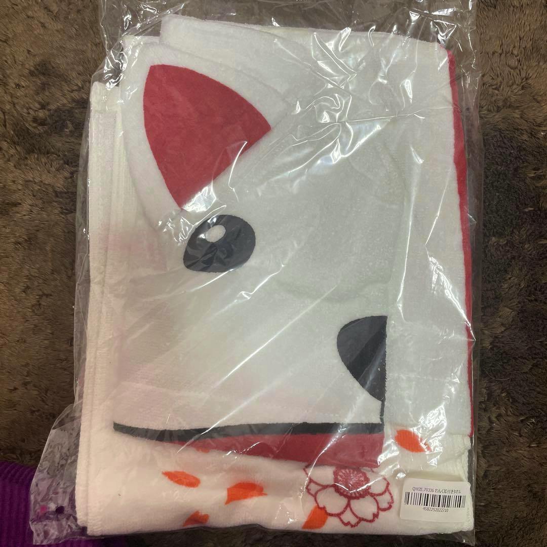 Folded white cotton bath towel with attached ear detail and printed face, packaged in clear plastic.
