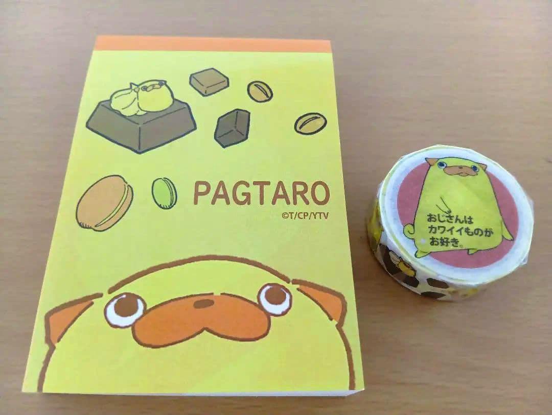 A yellow PAGTARO memo pad and a roll of matching masking tape placed on a wooden surface.
