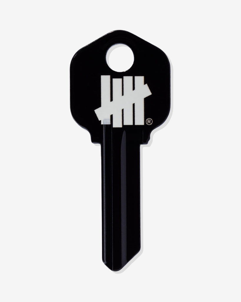 Black house key with a white UNDEFEATED tally-mark logo on the head.