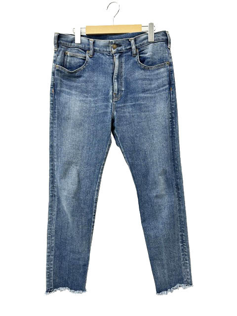 Front view of indigo blue men's denim jeans hanging on a hanger, showing raw cut-off frayed hems.