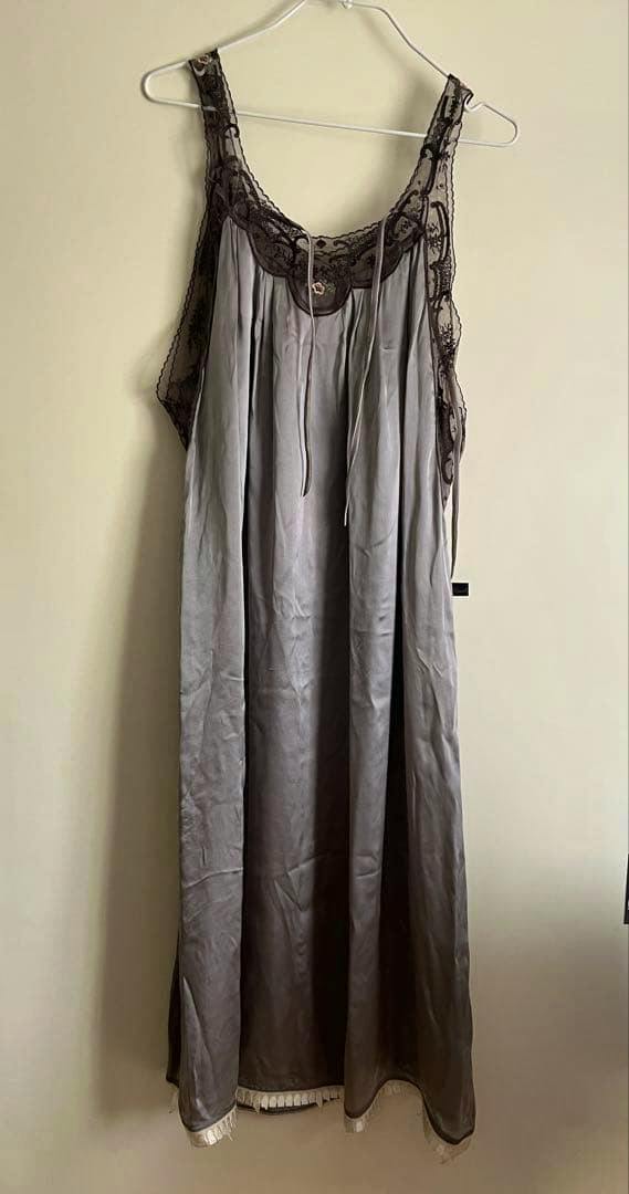 Long nylon camisole dress with lace-trimmed neckline hanging on a hanger against a plain wall.
