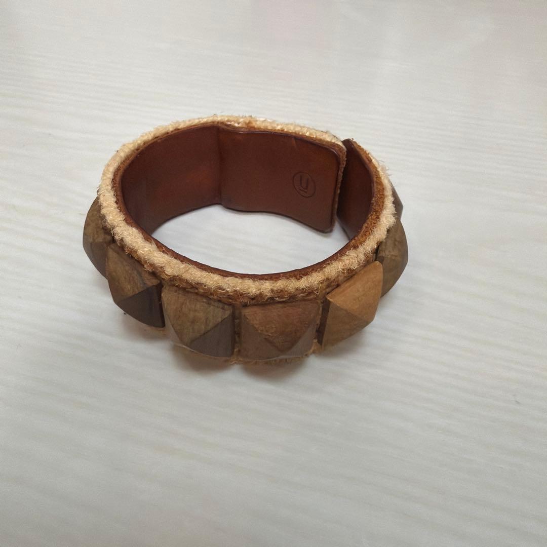 Brown cow leather bracelet with wooden pyramid decorations placed on a white surface.