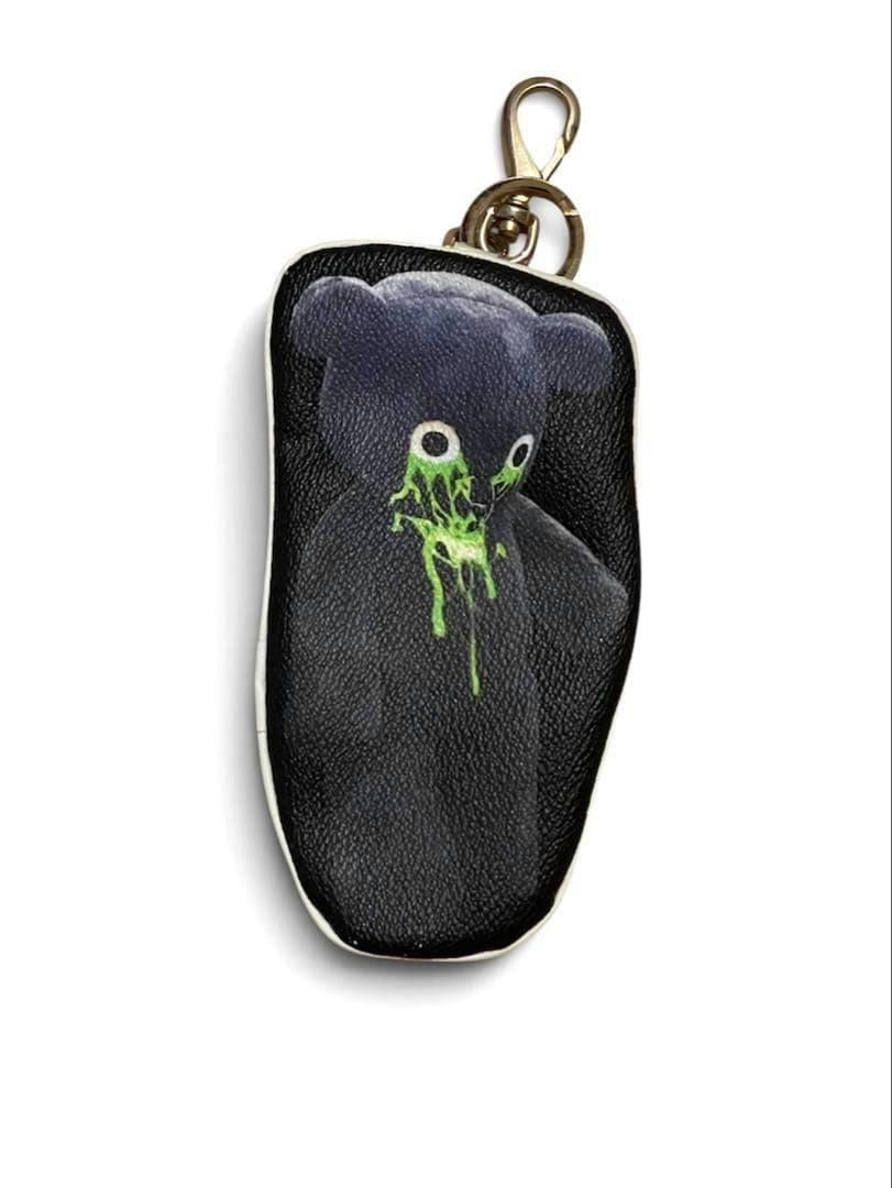 Front view of a black UNDERCOVER transfer pouch key holder with a printed bear graphic and a metal key clip.