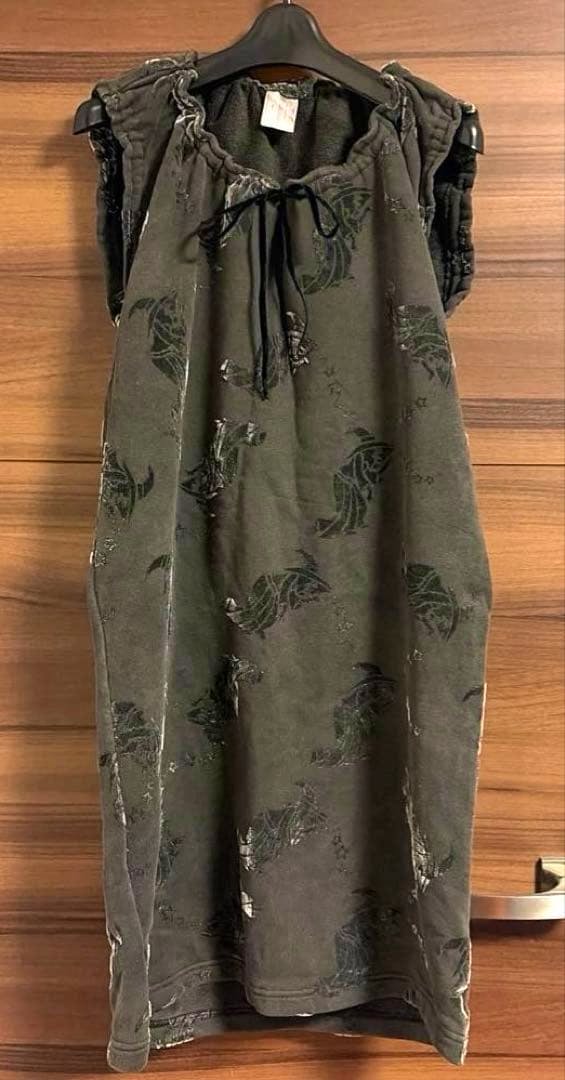 Full-length dark dress with witch and star patterns hanging on a hanger against a wooden background.