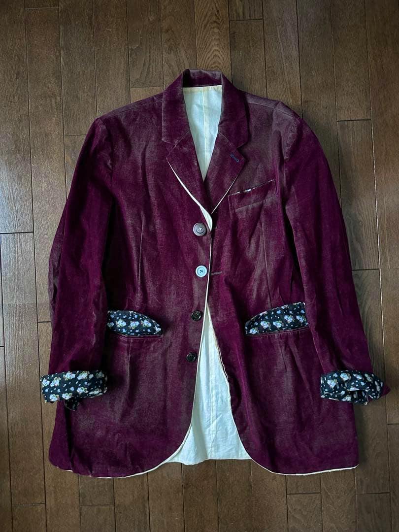 Burgundy women's cotton jacket laid flat on a wooden floor showing floral cuff lining and contrast trim.