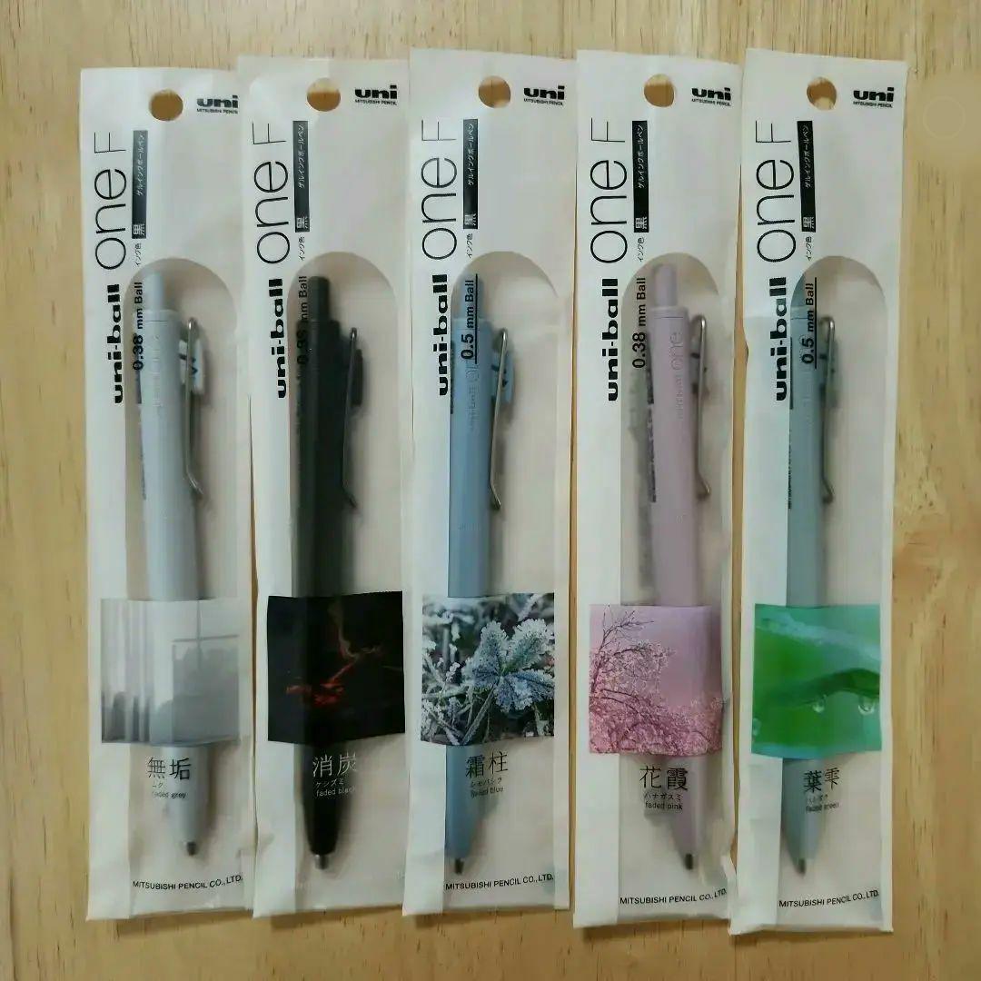 Five unopened Uni-ball One F ballpoint pens (0.38 mm and 0.5 mm) in original packaging arranged side by side.