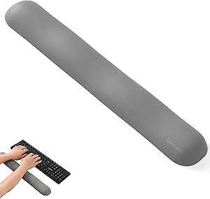 Gray ergonomic memory foam wrist rest for keyboards shown with hands at a keyboard.