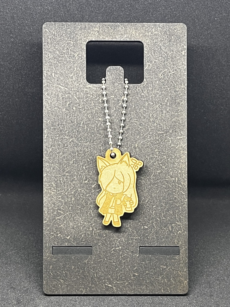 Wooden keychain featuring a chibi character design on a ball chain displayed on a gray stand.