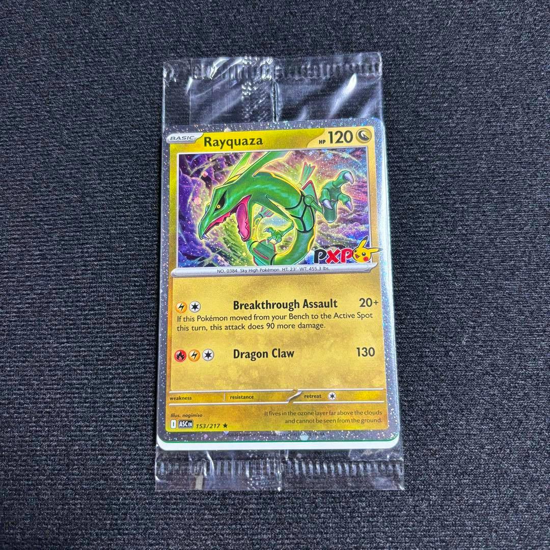 Front of a Rayquaza promo trading card (153/217 PXP) shown in a clear plastic sleeve on a dark textured surface.