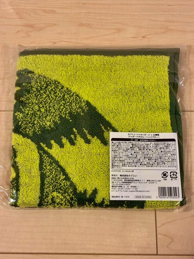 Folded, unopened jacquard towel with green and yellow helicopter-themed design shown in clear plastic packaging with label visible.