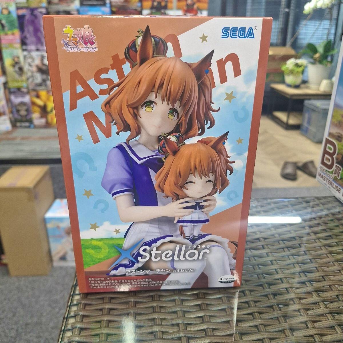 Front view of the unopened boxed XStellar Aston Marchan (おすわり) figure showing character artwork and the SEGA logo.