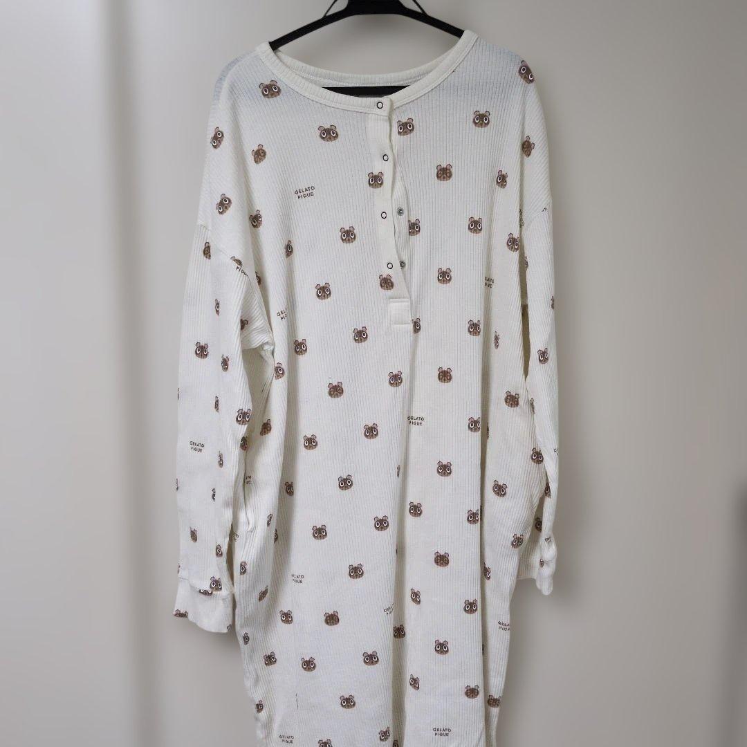 Front view of a white women's cotton jacquard one-piece pajama with small brown character faces hanging on a hanger.