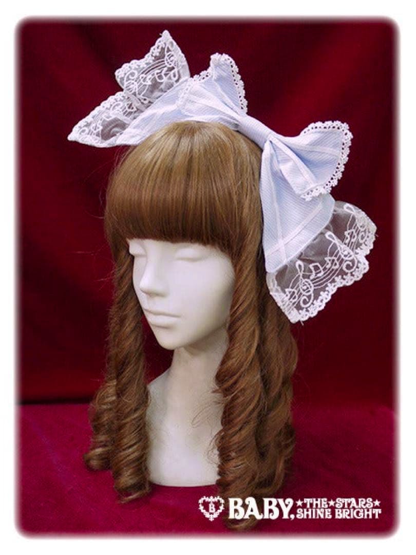 Mannequin head wearing a large bow-style headband decorated with lace embroidered with musical notes.