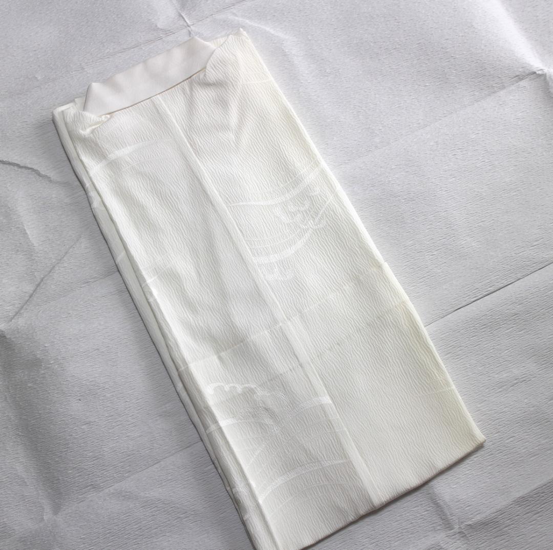 Folded white silk unlined nagajuban (long underkimono) showing a subtle wave pattern on a white background.