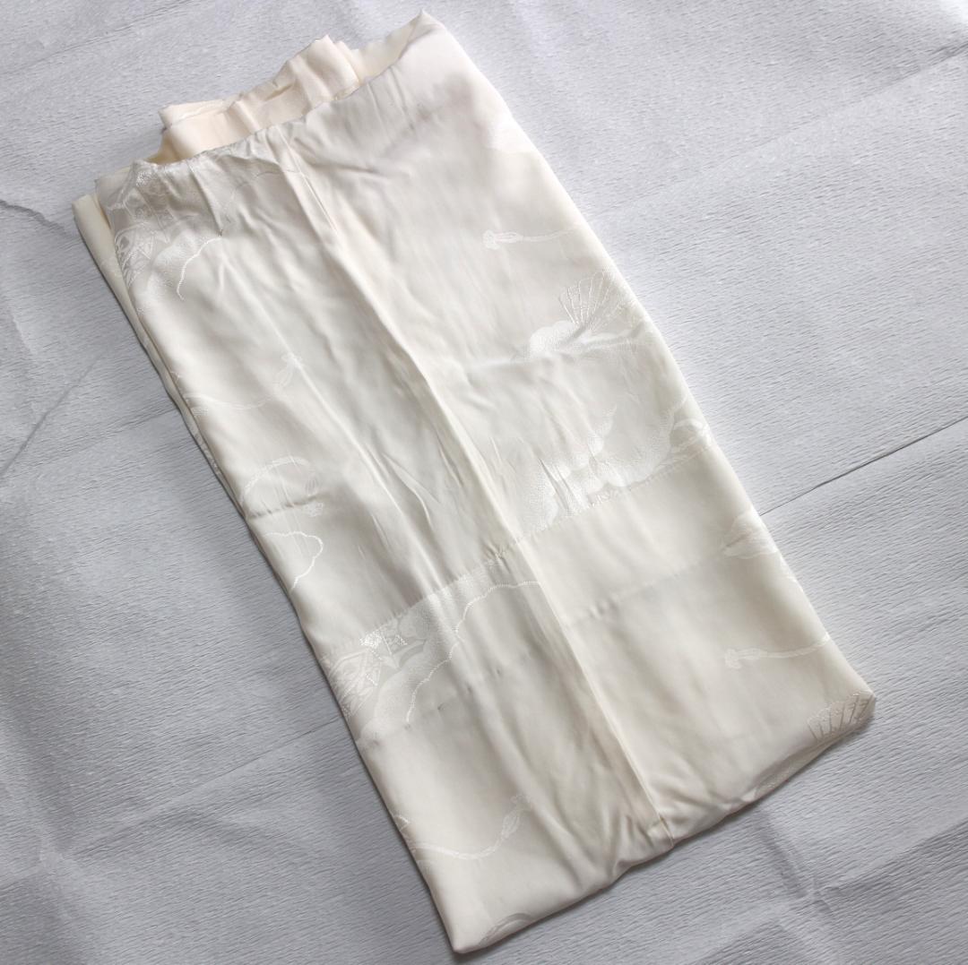 Folded white silk unlined nagajuban (long underkimono) showing a subtle kaioke (shell-bucket) woven pattern, laid flat on a surface.