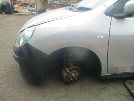 Left front fender of a silver car shown with the front wheel removed and the wheel well exposed.
