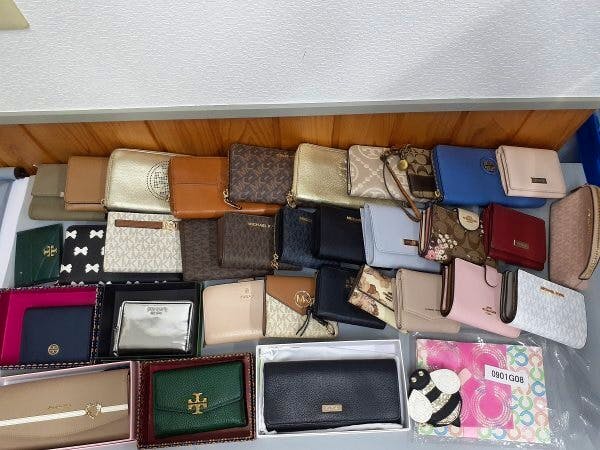 Assorted wallets, coin purses, and small cases from a bulk set laid out on a flat surface.