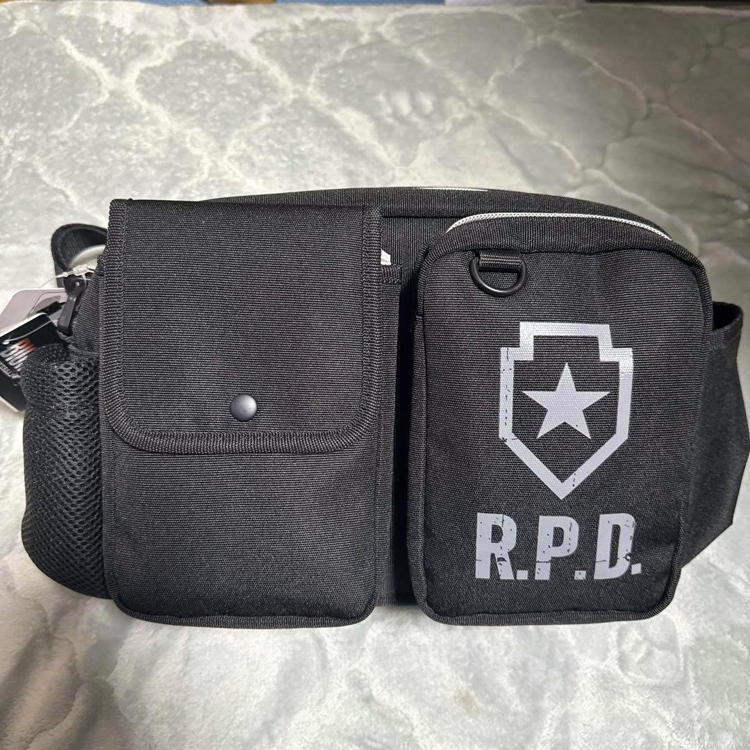 Front view of the USJ Biohazard 3-way bag showing two front pockets, a mesh side pocket, and an R.P.D. logo.