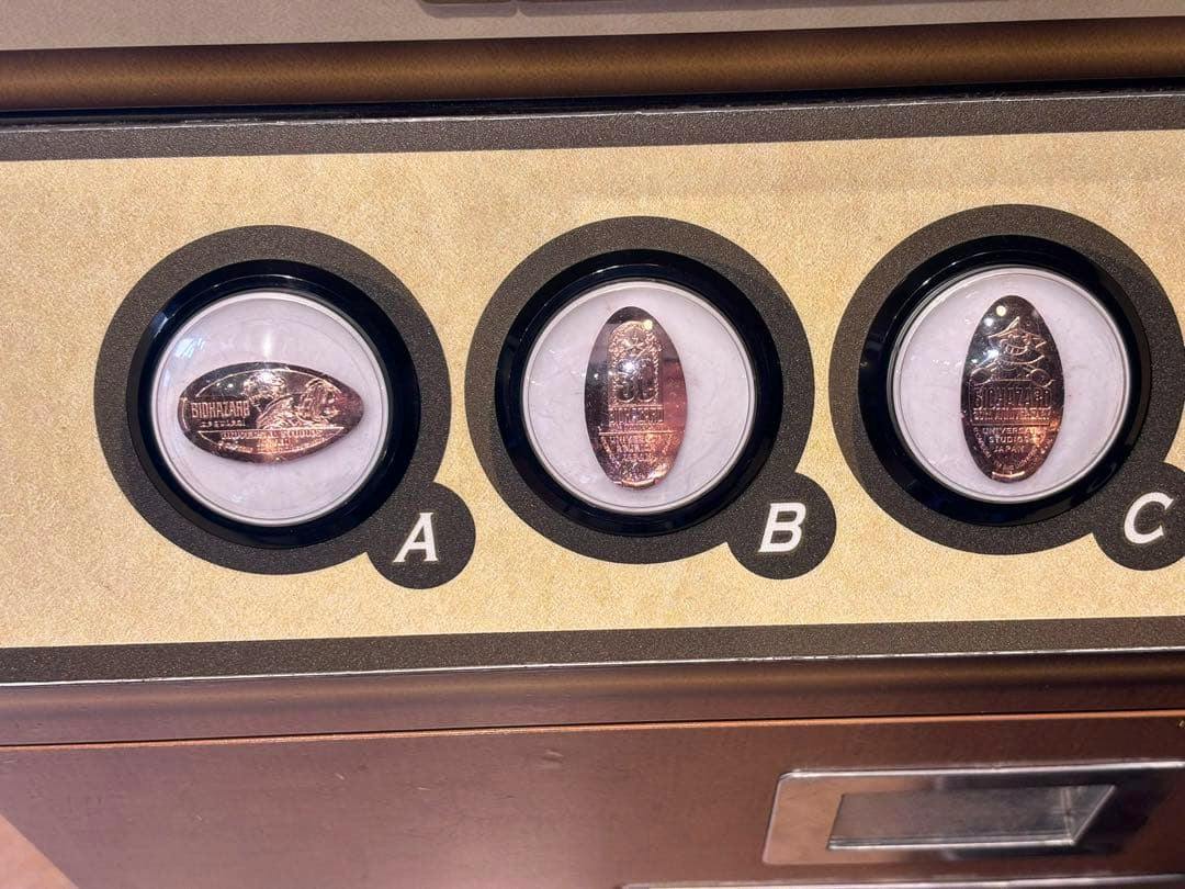 Three pressed souvenir medals for Biohazard 30th Anniversary shown in round display holders labeled A, B, and C.