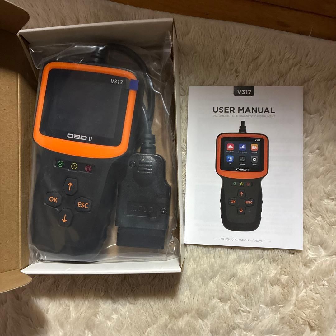 UYYE V317 OBD2 car diagnostic scanner in its box with the user manual beside it.